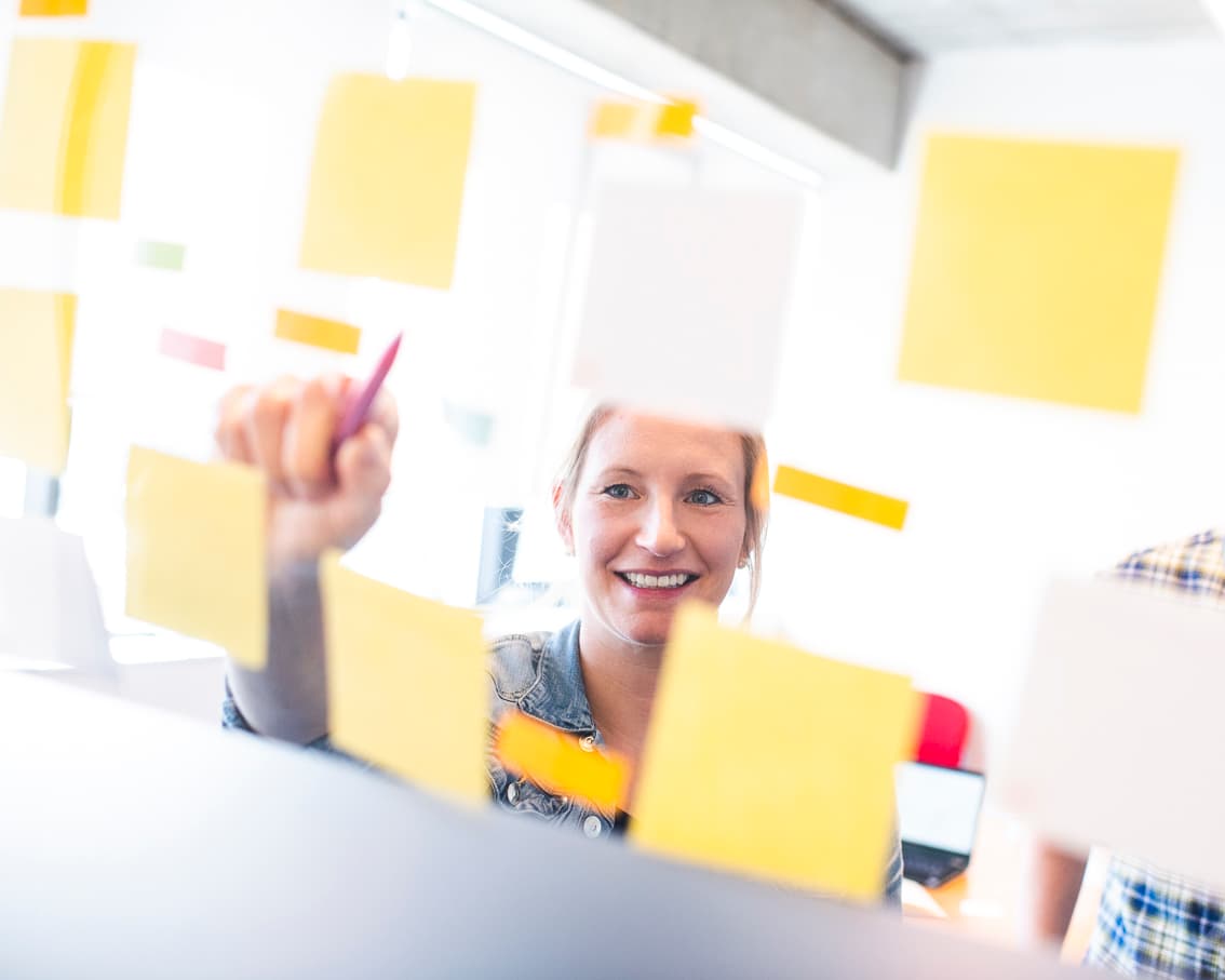Vrouw staat aan een Kanban-bord